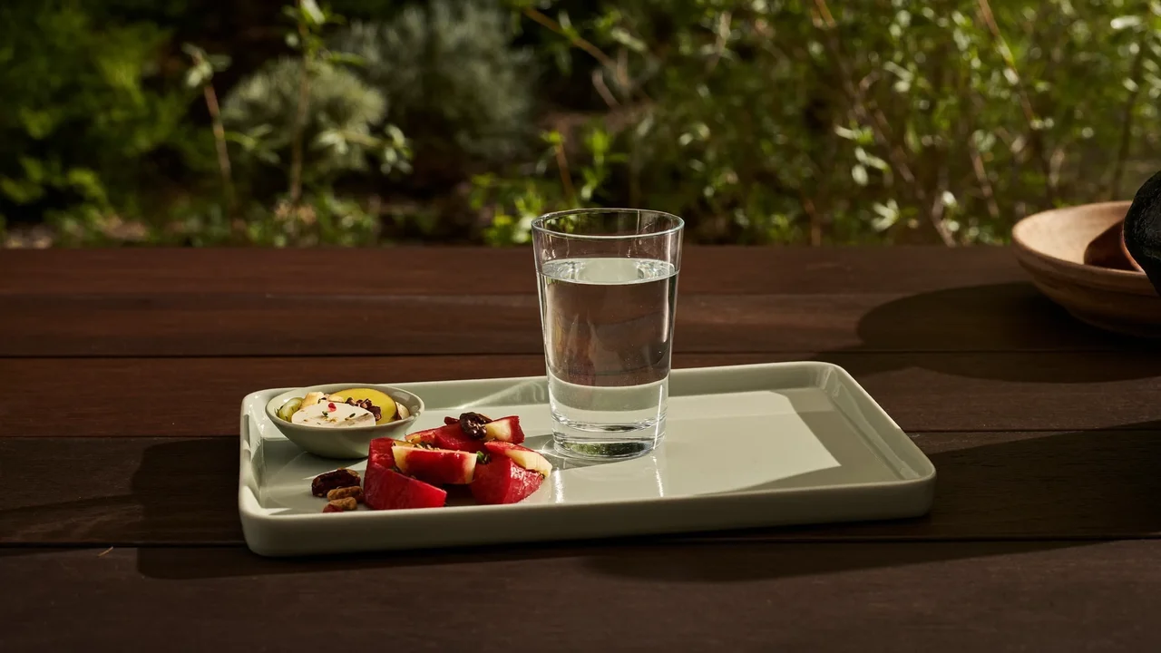 Bicchiere d'acqua e piatto di frutta e noci in giardino