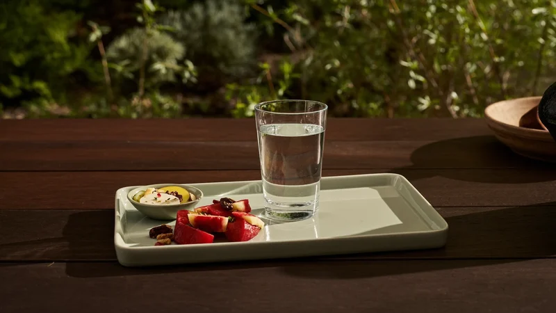Bicchiere d'acqua e piatto di frutta e noci in giardino